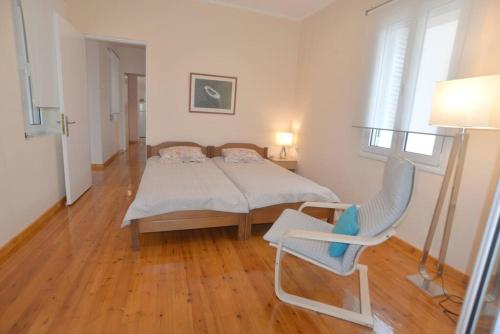 een slaapkamer met een bed en een stoel erin bij Bright and airy home 50 meters from the beach in Xylokastron