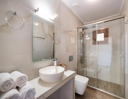 La salle de bains blanche est pourvue d'un lavabo et d'une douche. dans l'établissement 180 Villas, à Nydri
