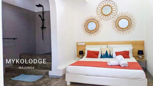 a bedroom with a bed with two mirrors on the wall at Mykolodge Majunga in Amborovy