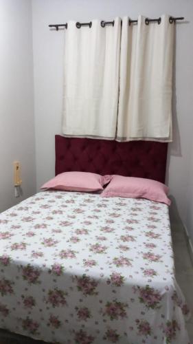 um quarto com uma cama com almofadas cor-de-rosa e uma janela em Casa Confortável em Caruaru