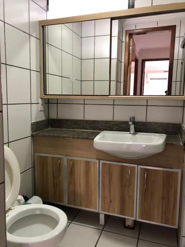 a bathroom with a sink and a toilet and a mirror at Porto de Iracema Residence in Fortaleza