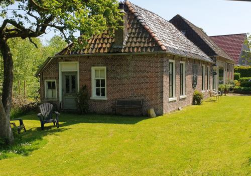 a small brick house with a lawn in front of it at Fakânsjehûs Sfeervol met fijne tuin in Irnsum