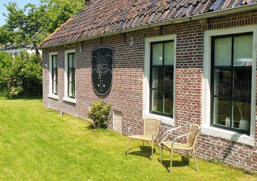 two chairs sitting outside of a brick building at Fakânsjehûs Sfeervol met fijne tuin in Irnsum