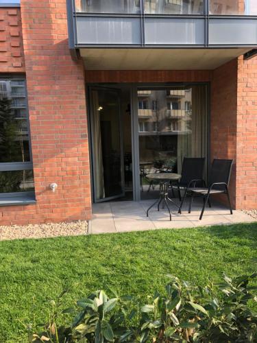 a brick building with a patio with two chairs and a table at Apartamenty 48 Scala in Gdańsk