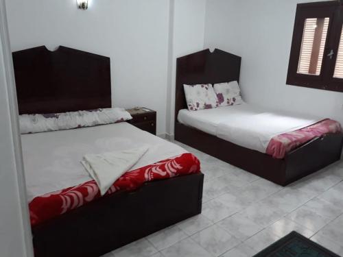 a bedroom with two beds with red and white sheets at Mama Africa in Hurghada