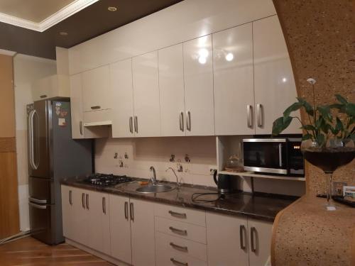 uma cozinha com armários brancos e um frigorífico de aço inoxidável em Апартаменти ''Комфорт'' em Kamianets-Podilskyi