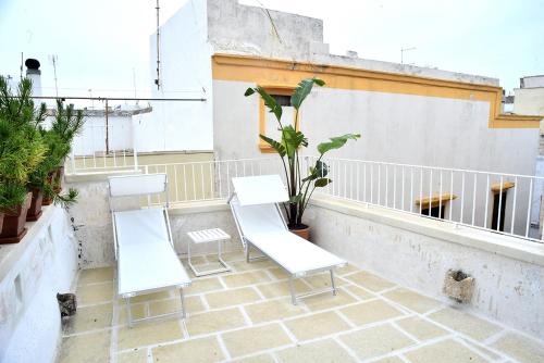 duas cadeiras brancas e um vaso de plantas numa varanda em B&B Tre Principi em Gallipoli