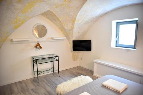 um quarto com uma cama, uma televisão e uma mesa em B&B Tre Principi em Gallipoli