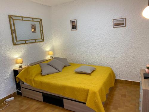 1 dormitorio con cama amarilla y espejo en la pared en Cassetta 92 Marie-Pierre, en Lumio
