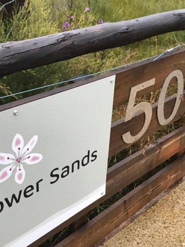 a sign for aowersowers stands on a wooden fence at Bicheno Wildflower Sands coastal retreat in Bicheno