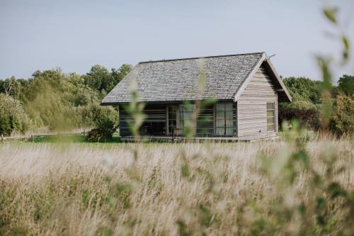 an old house in the middle of a field at Durbes Atvari - brīvdienu mājas ar saunu in Durbe