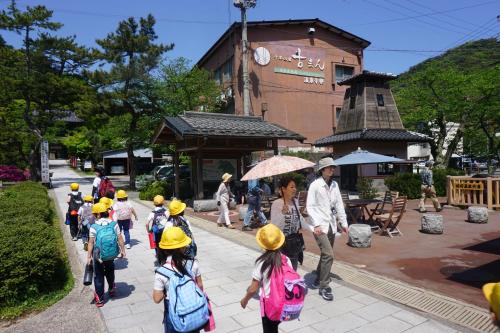 a group of children wearing yellow hats walking down a sidewalk at Morizuya in Toyooka