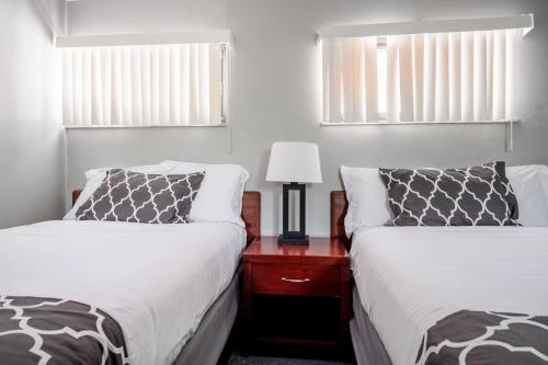 ein Schlafzimmer mit 2 Betten und einem Tisch mit einer Lampe in der Unterkunft Holiday Retreat Detroit Ford Flat Rock Assembly in Woodhaven