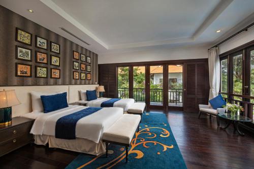 a bedroom with two beds and a blue rug at Abogo Resort Villa Beach Premium in Da Nang