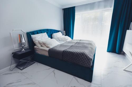 sypialnia z łóżkiem z niebieskimi zasłonami i oknem w obiekcie EnergyApart 26 w mieście Międzywodzie