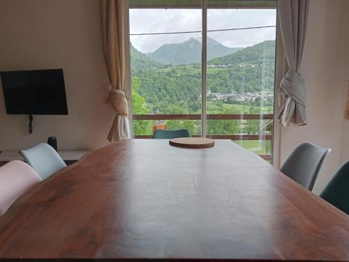 una gran mesa de madera con sillas y una gran ventana en Châlet montagne 6 personnes, en Laruns