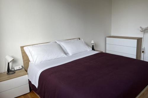 1 dormitorio con 1 cama grande con sábanas blancas y moradas en la casa di Antoine, en Cesano Maderno