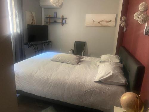 une chambre avec un lit avec des draps blancs et une télévision dans l'établissement Duplex F4 sanguinaires à 5 mn de la plage, à Ajaccio