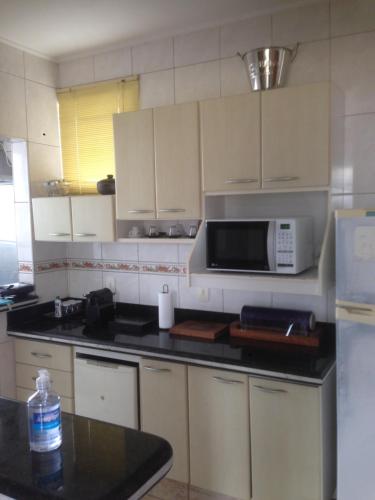 a kitchen with white cabinets and a microwave at Aconchego 2 - Suíte in Varginha
