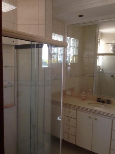 uma casa de banho com um chuveiro, um lavatório e um espelho. em Aconchego 2 - Suíte em Varginha