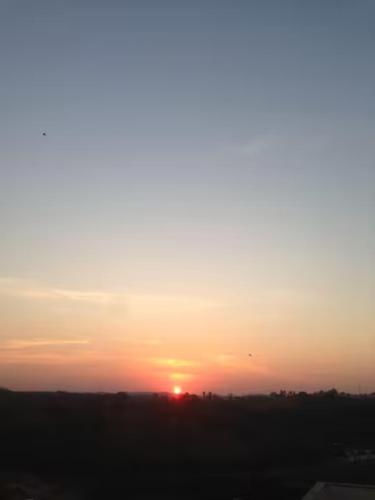 una puesta de sol con la puesta de sol en el horizonte en Aconchego 2 - Suíte, en Varginha