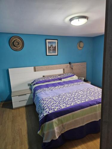 a bedroom with a bed with a blue wall at El txoko de onso in Santibáñez de la Peña