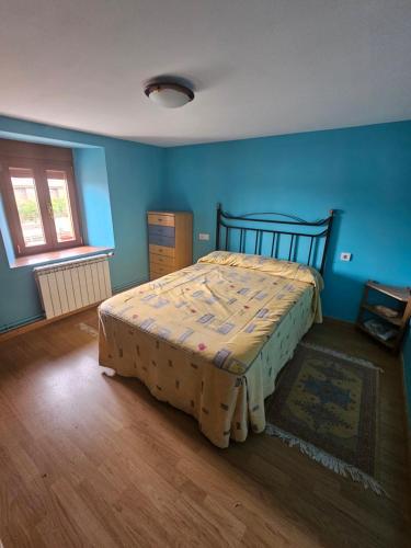 1 dormitorio con 1 cama en una habitación azul en El txoko de onso, en Santibáñez de la Peña