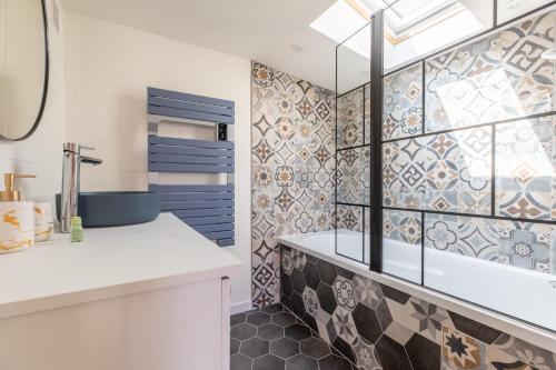 La salle de bains est pourvue d'un lavabo et d'une douche revêtue de carrelage. dans l'établissement La Maisonnette - Confort & Calme, à Lezoux