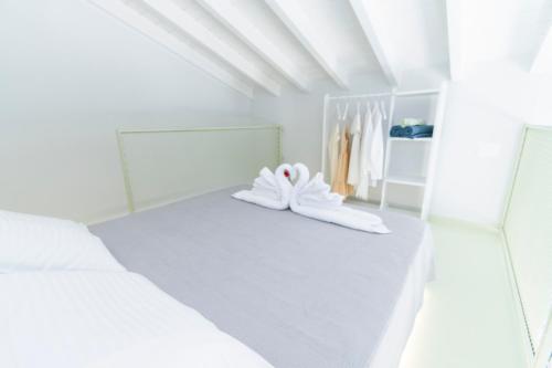 een witte slaapkamer met 2 bedden en een spiegel bij LA CASA DI MARCONI in Symi
