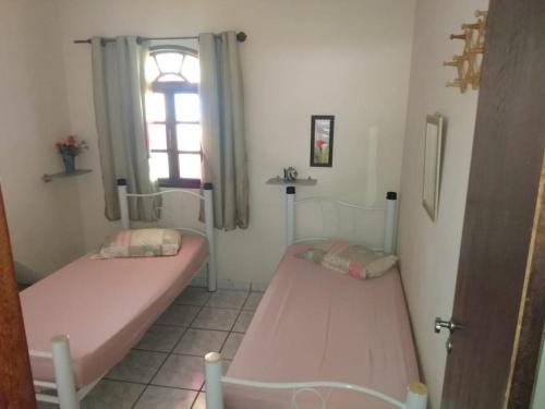 dwa łóżka w pokoju z oknem w obiekcie Bragança's Houses w mieście Cabo Frio