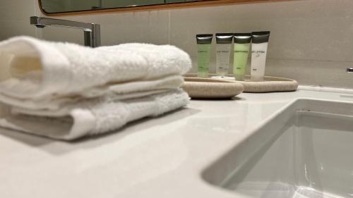 een witte handdoek op een badkamerbar naast een wastafel bij Charming 1-Bed Loft with Serene Pool View, Steps from the Beach in Abu Dhabi