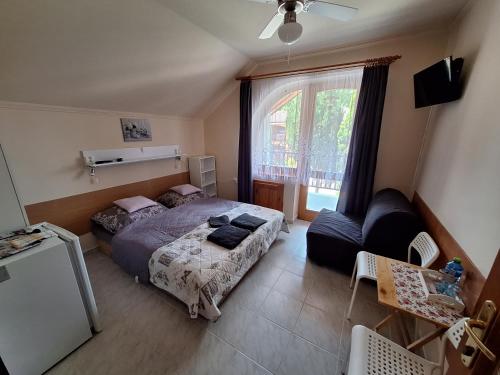 1 dormitorio con cama, sofá y ventana en Vila ETIJA en Veľký Meder