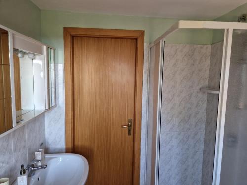ein Badezimmer mit einer Dusche und einem Waschbecken sowie einer Holztür in der Unterkunft franci e aurora house in Capo dʼOrlando
