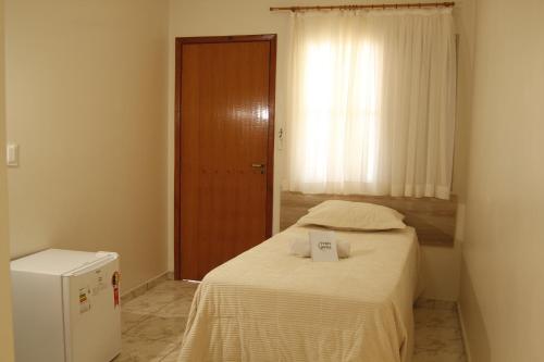 a small bedroom with a bed with a sign on it at Turis Hotel Centro in Campo Grande