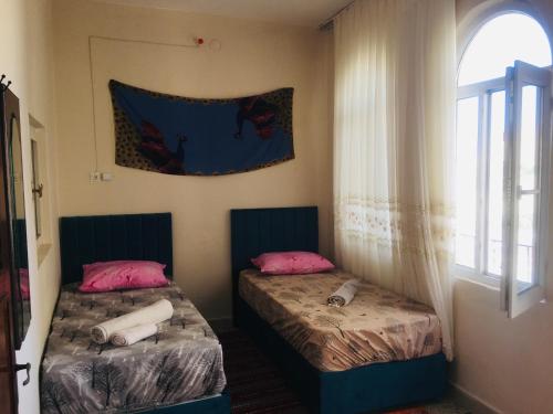 two beds sitting in a room with a window at Rosa Hostel in Mardin