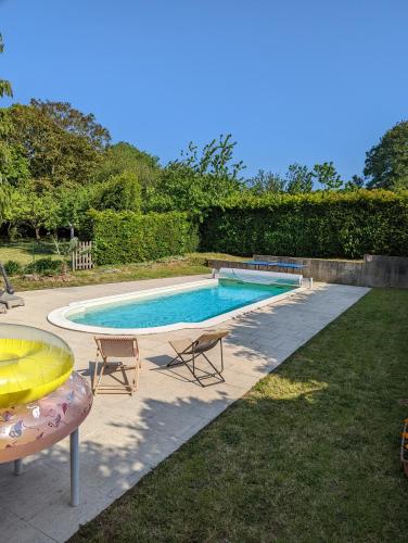 une piscine avec deux chaises et une table dans l'établissement Breizh home A la Boissière, à Merléac