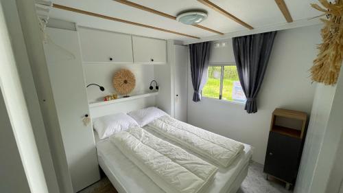 a bedroom with a white bed and a window at PURE - Chalet Zeeland - garden out of sight in Hoek