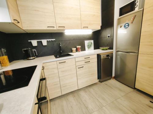 cocina con armarios de madera y nevera de acero inoxidable en Apartament Radio Tower, en Gliwice