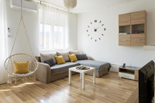 a living room with a couch and a clock on the wall at Apartment Pemper - Self check in and check out in Otočac