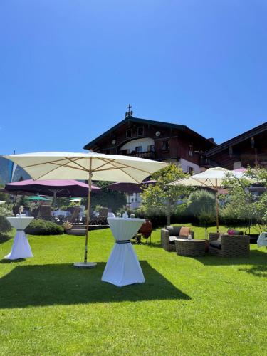 a group of tables and umbrellas in the grass at Hotel Maier zum Kirschner in Rottach-Egern