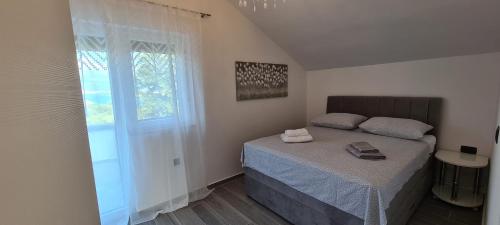 ein kleines Schlafzimmer mit einem Bett und einem Fenster in der Unterkunft Apartments Rajna in Čižići