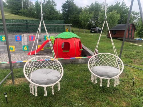 two swings in front of a playground with a tent at Seosko domacinstvo Becirovic - Kukulik lodgings in Bijelo Polje