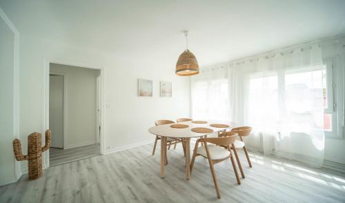 a white dining room with a table and chairs at La vie en Beige - Appartement à Chalon-sur-Saône in Chalon-sur-Saône