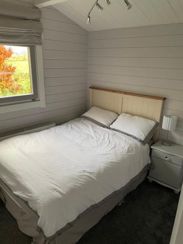 a bedroom with a white bed and a window at Country Cabin Omagh in Omagh