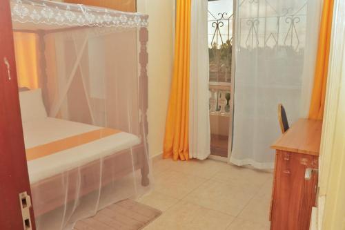 Un dormitorio con una cama con dosel y una ventana. en Home Away from Home, en Mombasa