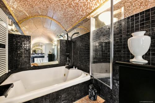 a bathroom with a white tub and black tiles at Villa Isidoro ampio parco piscina privata in Verona