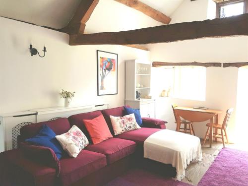 a living room with a red couch with colorful pillows at Old Bake House Cottage @ Cwm Mill in Michaelchurch Escley