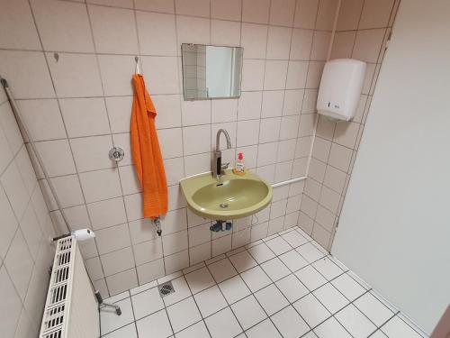 uma casa de banho com um lavatório e uma toalha laranja em Ferienwohnung Linden 180 em Willich
