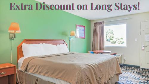 a hotel room with a bed and a sign that reads extra discount on long stays at Economy Inn By OYO Ashburn in Ashburn