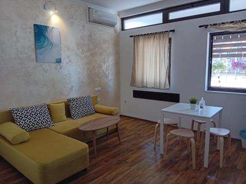 a living room with a yellow couch and a table at Fiori Apartment in Gevgelija